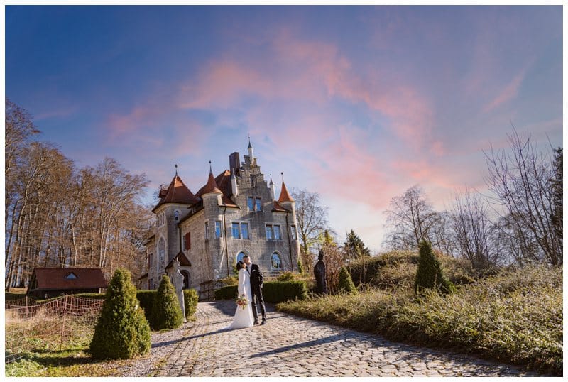 Brautpaar vor dem Schloss Albgut Münsingen. Links und rechts sind Zypressen. Der Himmel wie im Märchen