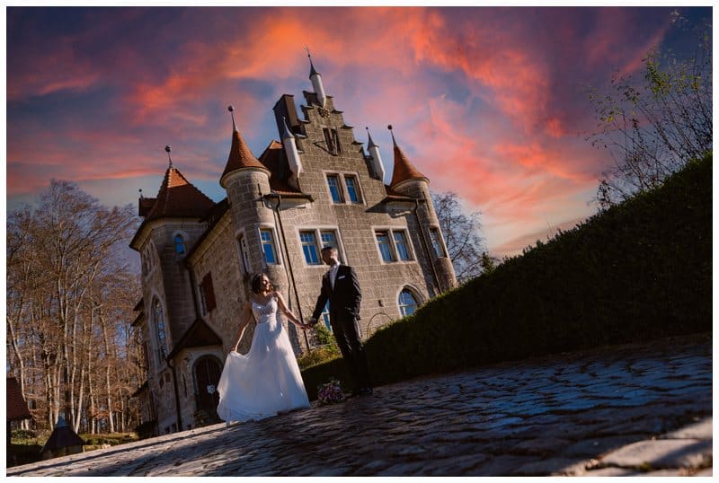 Hochzeitsfoto auf Schloss Albgut in Münsingen. Brautpaar tanzt vor Disney Schloss mit rotem Himmel